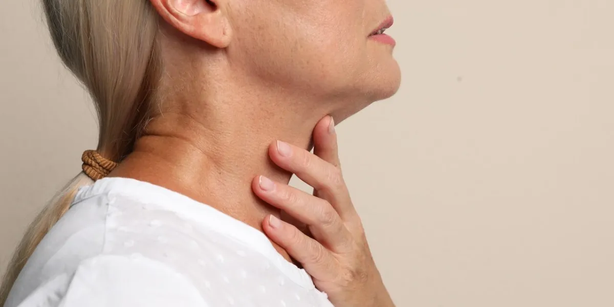 mature woman doing thyroid self examination on beige background closeup mature woman doing thyroid self examination on beige background closeup