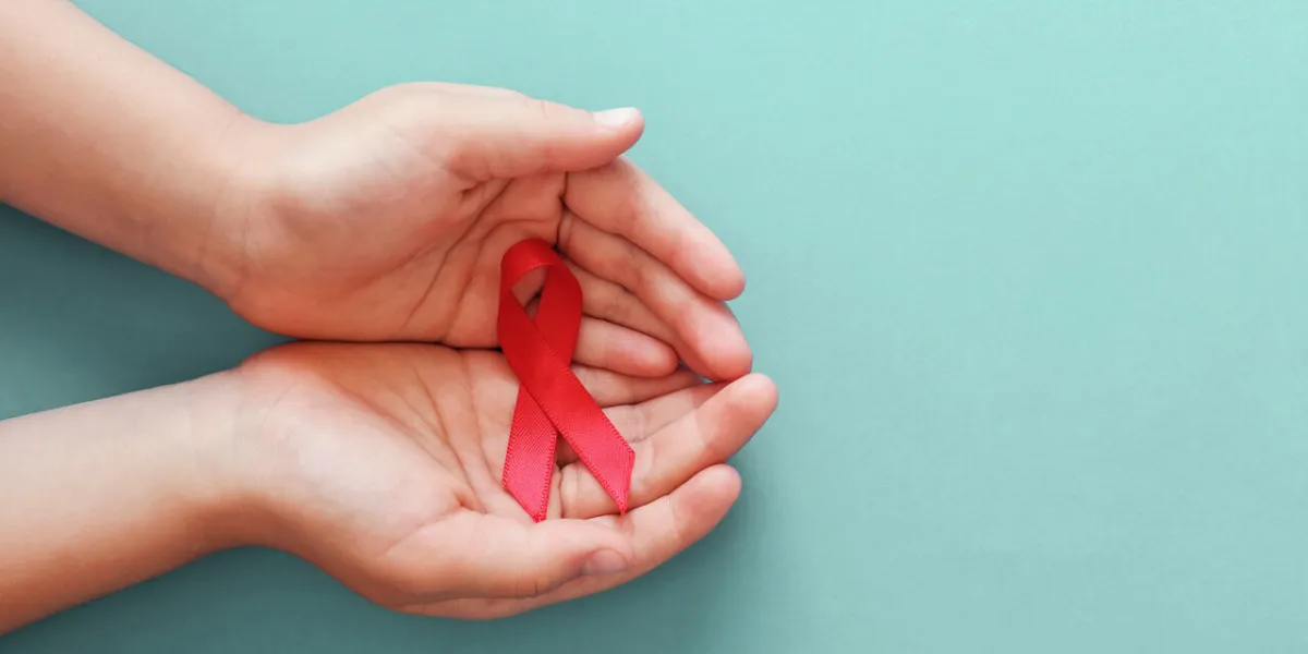 hands holding red ribbon on blue background, hiv awareness concept, world aids day, world hypertension day hands holding red ribbon on blue background, hiv awareness concept, world aids day, world hypertension day