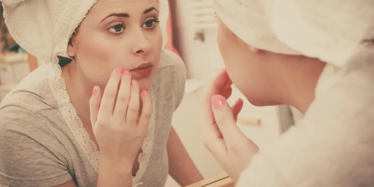 woman looking at her reflection in mirror thinking about her complexes having serious face expression, analyzing face skin complexion woman looking at her reflection in mirror thinking about her complexes having serious face expression, analyzing face skin complexion