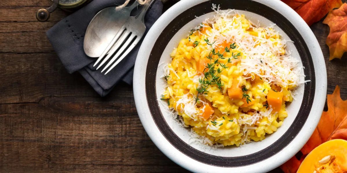 pumpkin risotto with thyme and parmesan cheese against dark wooden background overhead view pumpkin risotto with thyme and parmesan cheese against dark wooden background overhead view