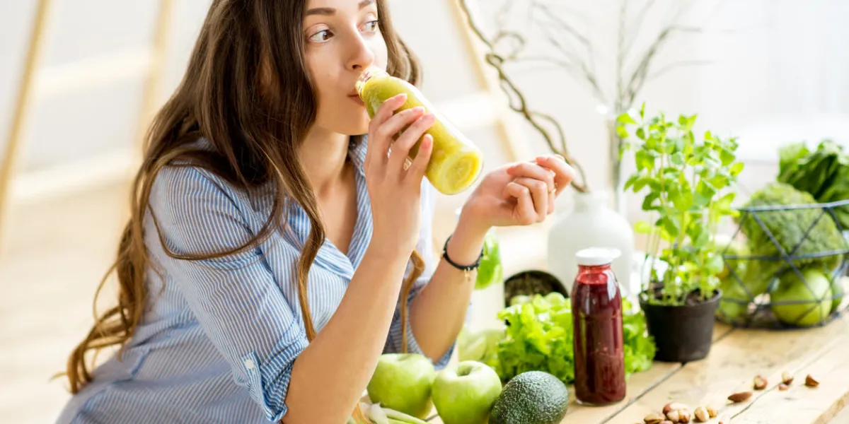 beautiful woman sitting with healthy green food and drinking smoothie at home vegan meal and detox concept beautiful woman sitting with healthy green food and drinking smoothie at home vegan meal and detox concept