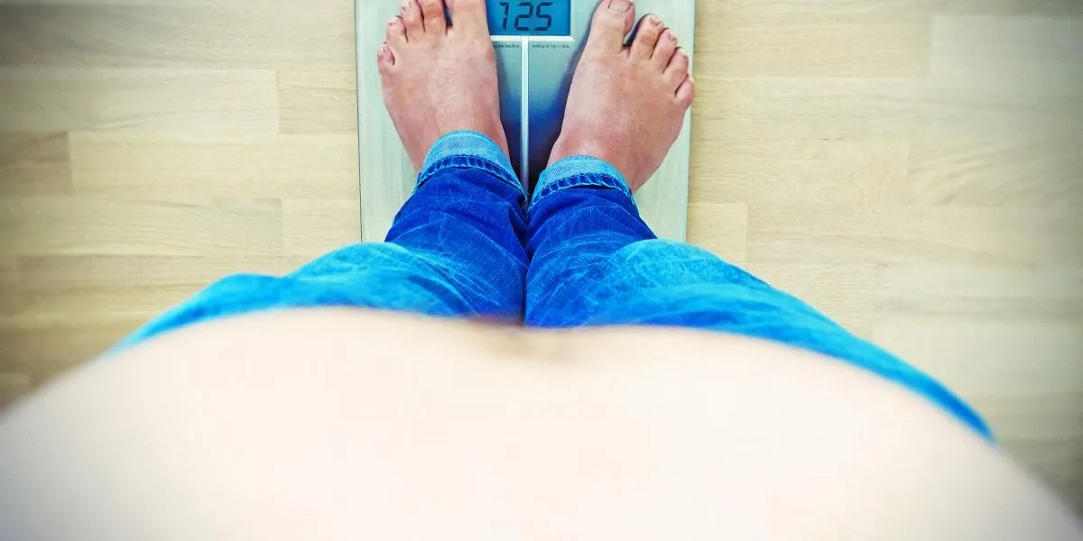 Übergewicht - mann mit bauch auf einer waage Übergewicht - mann mit bauch auf einer waage