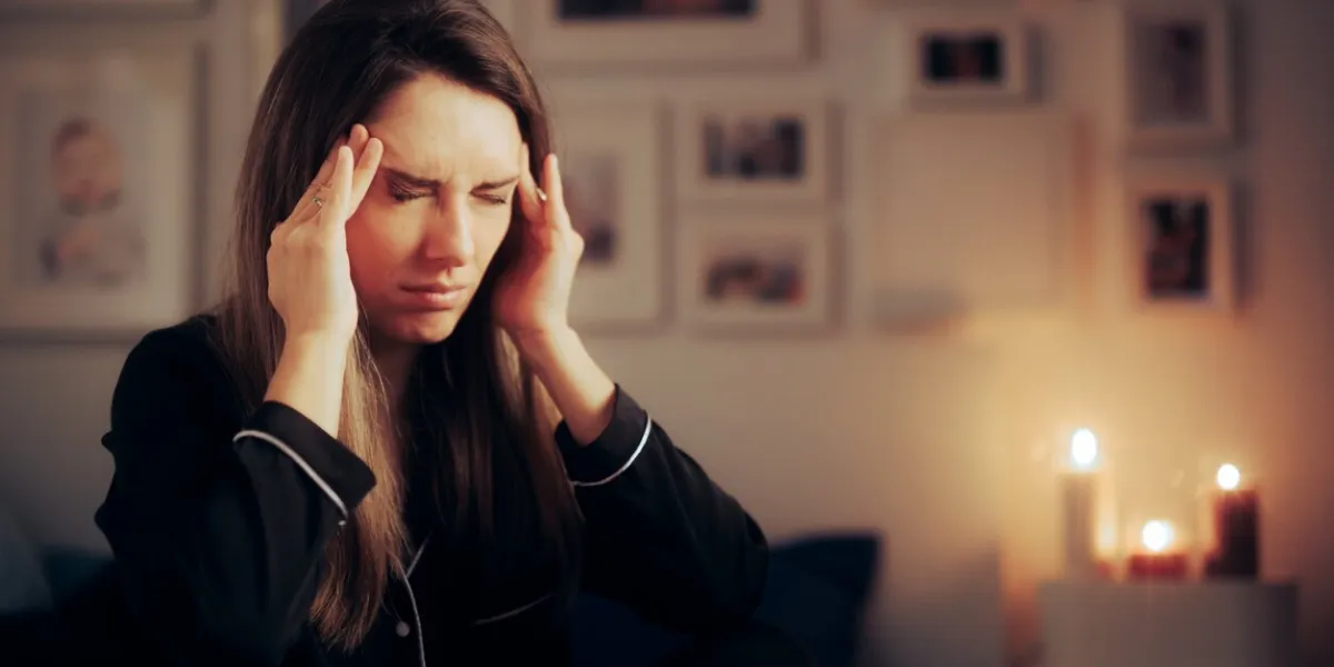 stressed woman suffering a migraine at night before going to sleep stressed woman suffering a migraine at night before going to sleep
