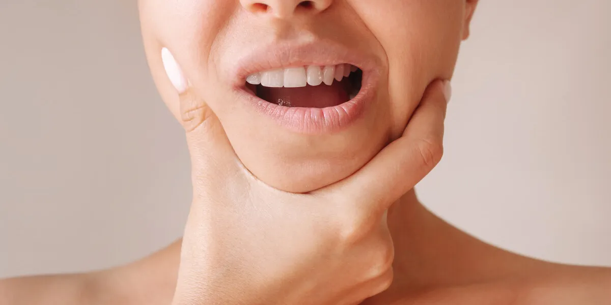 cropped shot of a young woman suffering from jaw pain holding he cropped shot of a young woman suffering from jaw pain holding he