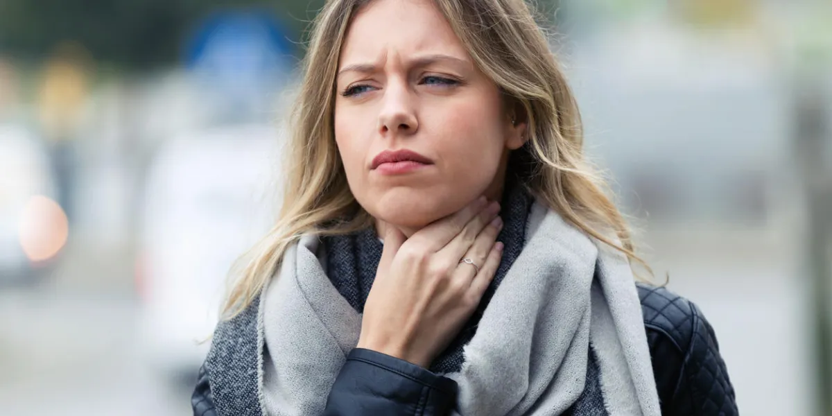 shot of illness young woman with terrible throat pain walking to the street shot of illness young woman with terrible throat pain walking to the street