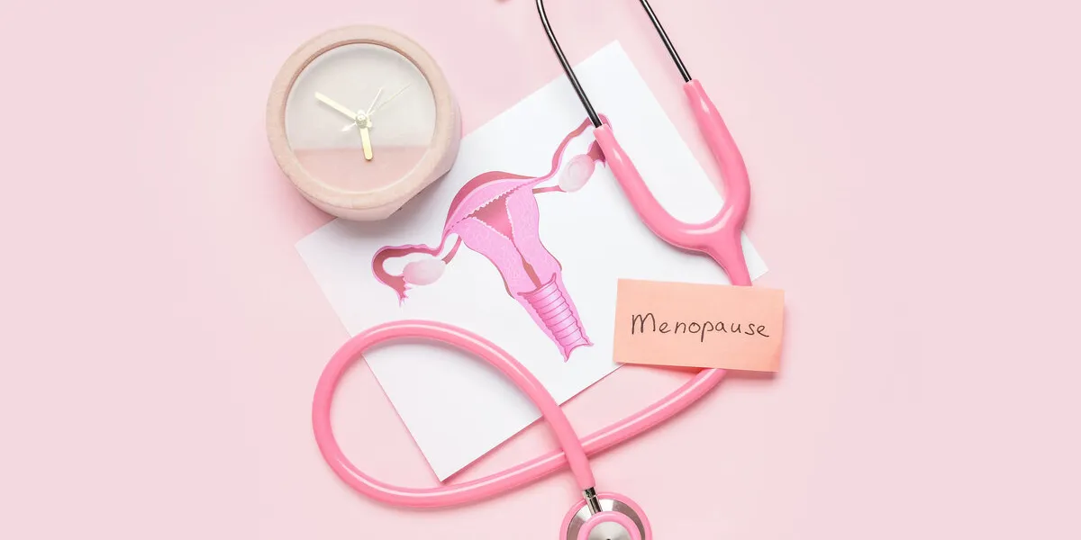 papers with word menopause, uterus, stethoscope and alarm clock on pink background papers with word menopause, uterus, stethoscope and alarm clock on pink background